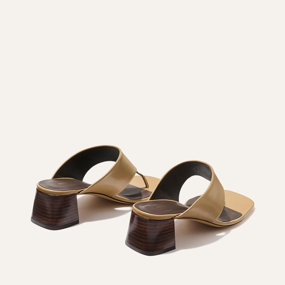 The Deia 50 - Praline Nappa by Margaux: tan open-toe sandals with wide straps, dark insoles, and chunky low wooden block heels, shown on a light background.