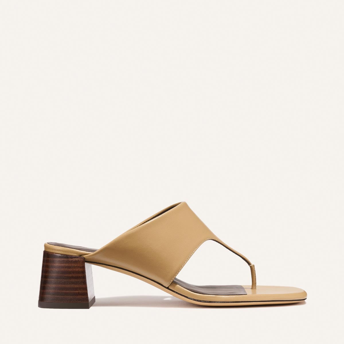 The Deia 50 - Praline Nappa by Margaux is a tan open-toe heeled sandal with a wide upper strap, toe post, and block heel with a wood-like finish, shown against a plain light background.