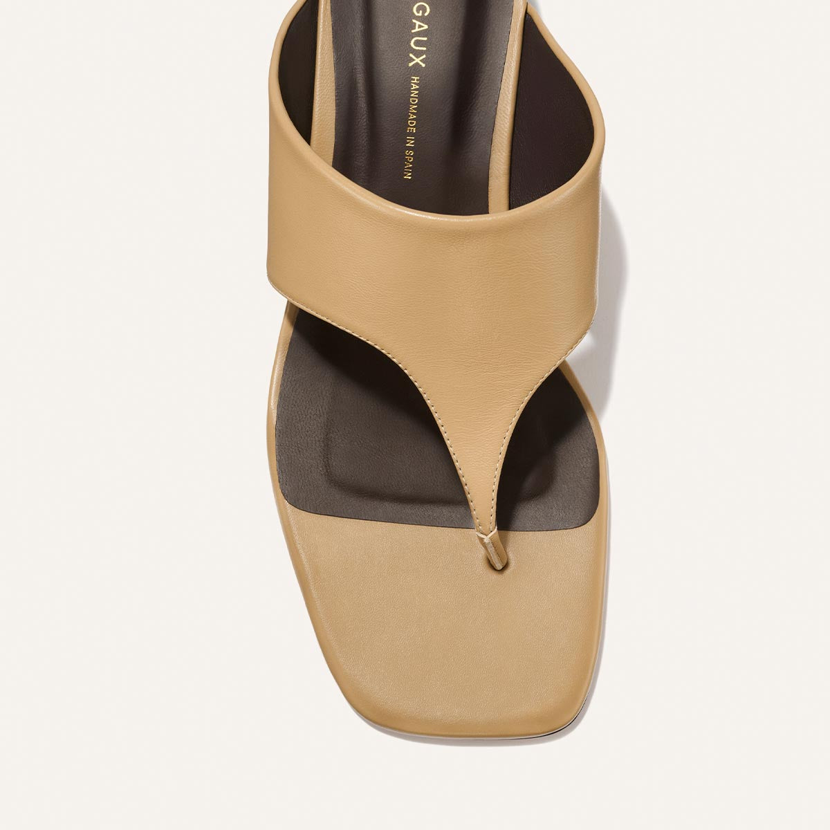 Top view of The Deia 50 - Praline Nappa by Margaux: a beige, square-toe sandal with a wide strap and toe thong, showcasing a minimalist modern design.