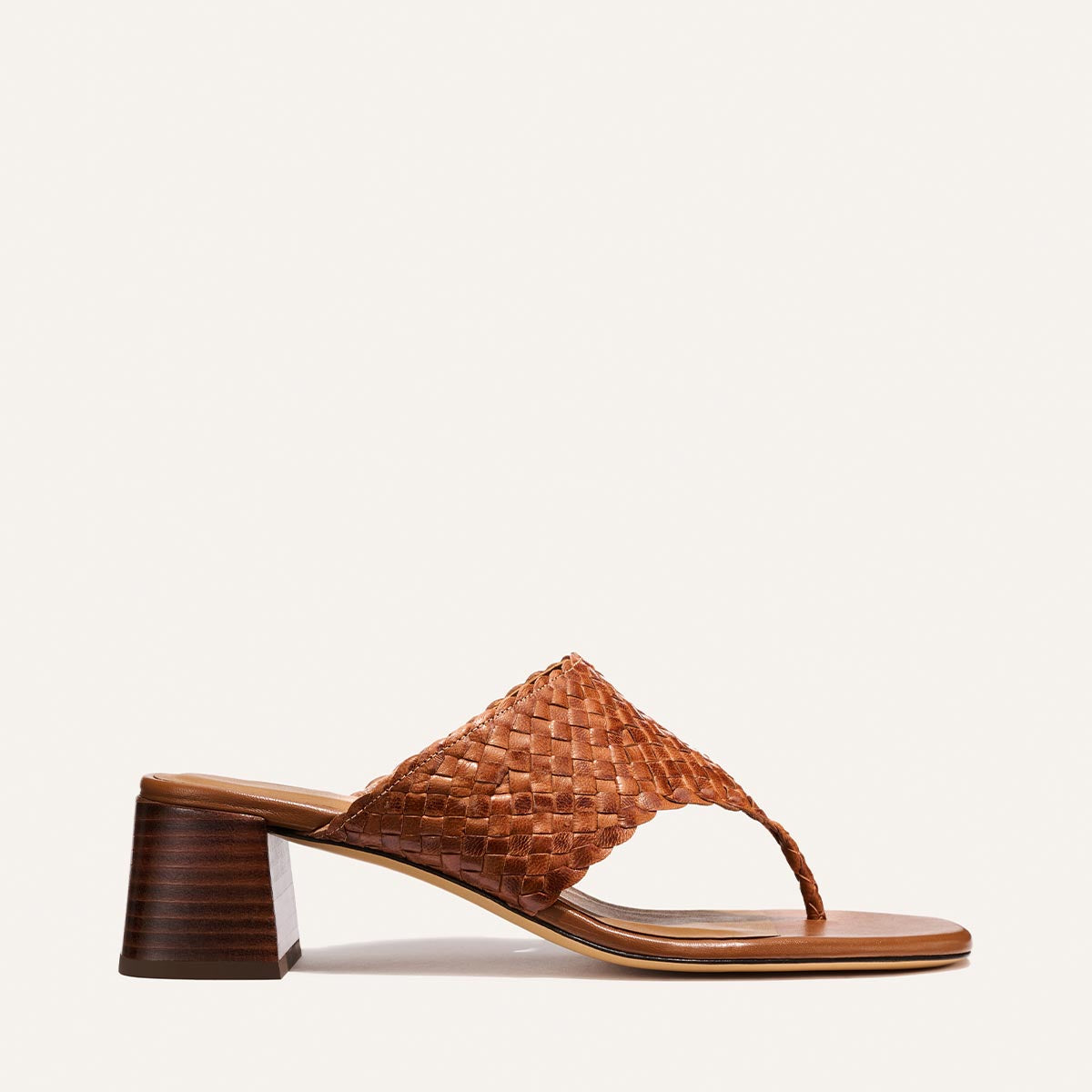 The Deia 50 - Saddle Woven Leather by Margaux is a brown woven leather sandal with an open toe, thong strap, and low block heel, shown against a plain light background.