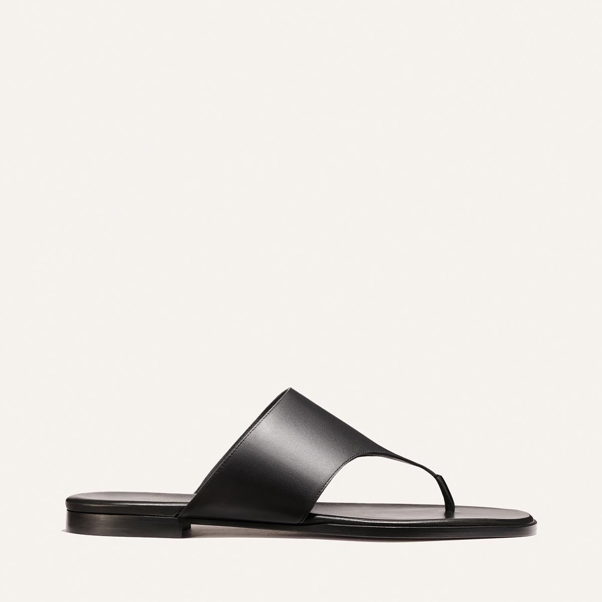 The Deia - Black Nappa by Margaux is a black leather thong sandal featuring a wide top strap and flat sole, shown on a plain white background.