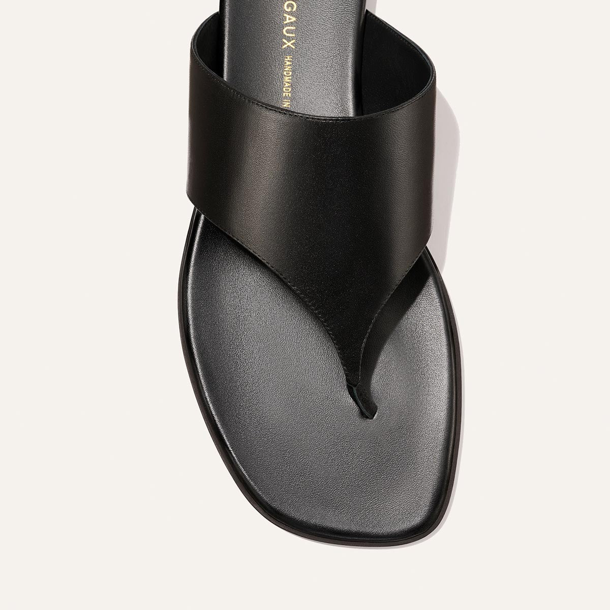 A close-up of The Deia - Black Nappa by Margaux, a black leather sandal with a wide strap and square toe, showcasing a minimalist, modern design.