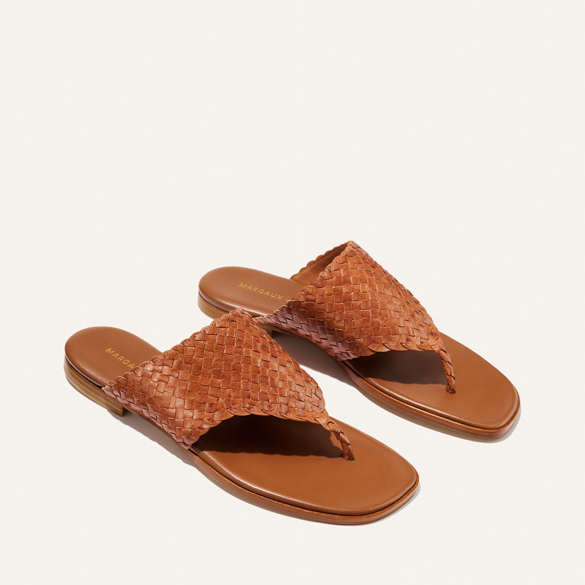 Pair of brown woven sandals on a white background