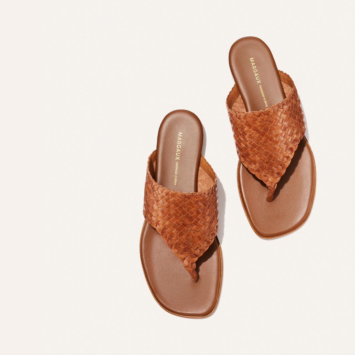Pair of brown woven sandals on a light beige background