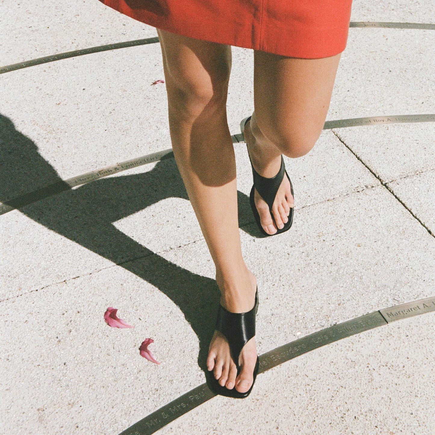 Person wearing black block heeled sandals on a concrete surface