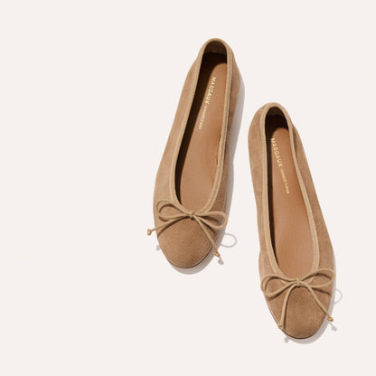 The Demi - Biscotti Suede by Margaux are handmade tan suede ballet flats with rounded toes and petite bow accents, crafted in Spain and shown on a light background.