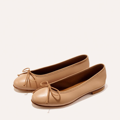 The Demi - Dune Nappa by margaux-development: beige leather ballet flats with rounded toes, brown soles, and petite front bows, shown on a plain light background.