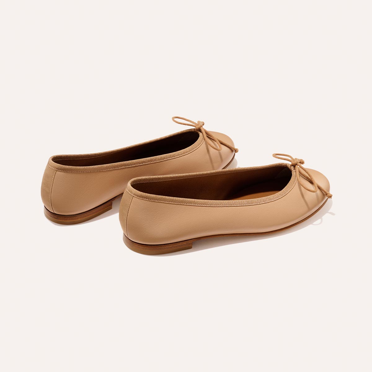 The Demi - Dune Nappa by margaux-development: tan leather ballet flats with small front bows and brown soles, shown on a light background.