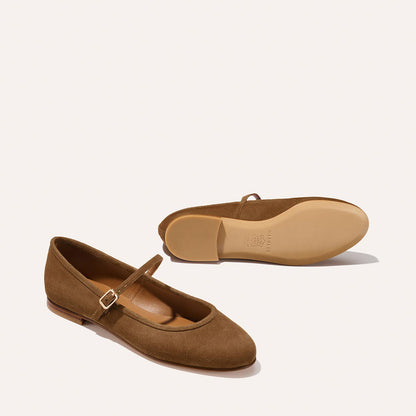 The Demi Jane - Cedar Suede by margaux-development: one brown suede Mary Jane flat with buckle stands upright, while its chic pair lies on its side, sole visible, both set against a plain light background.