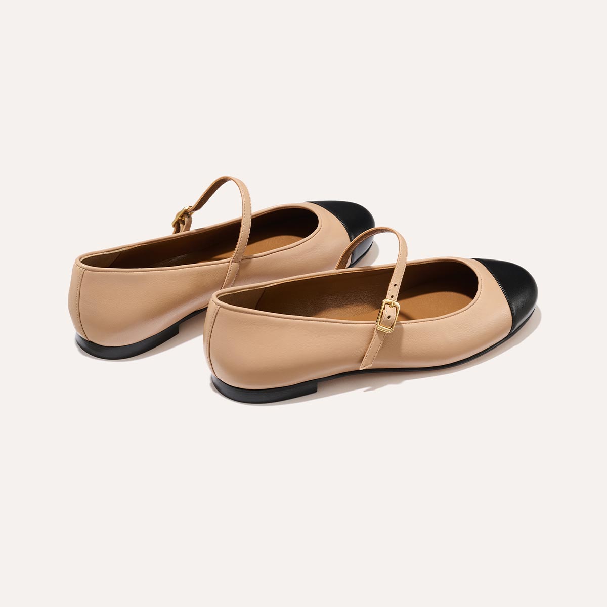 The Demi Jane in smooth Dune nappa leather, a ballet flat with a rounded toe, black cap-toe detail  and an adjustable strap for a secure fit.