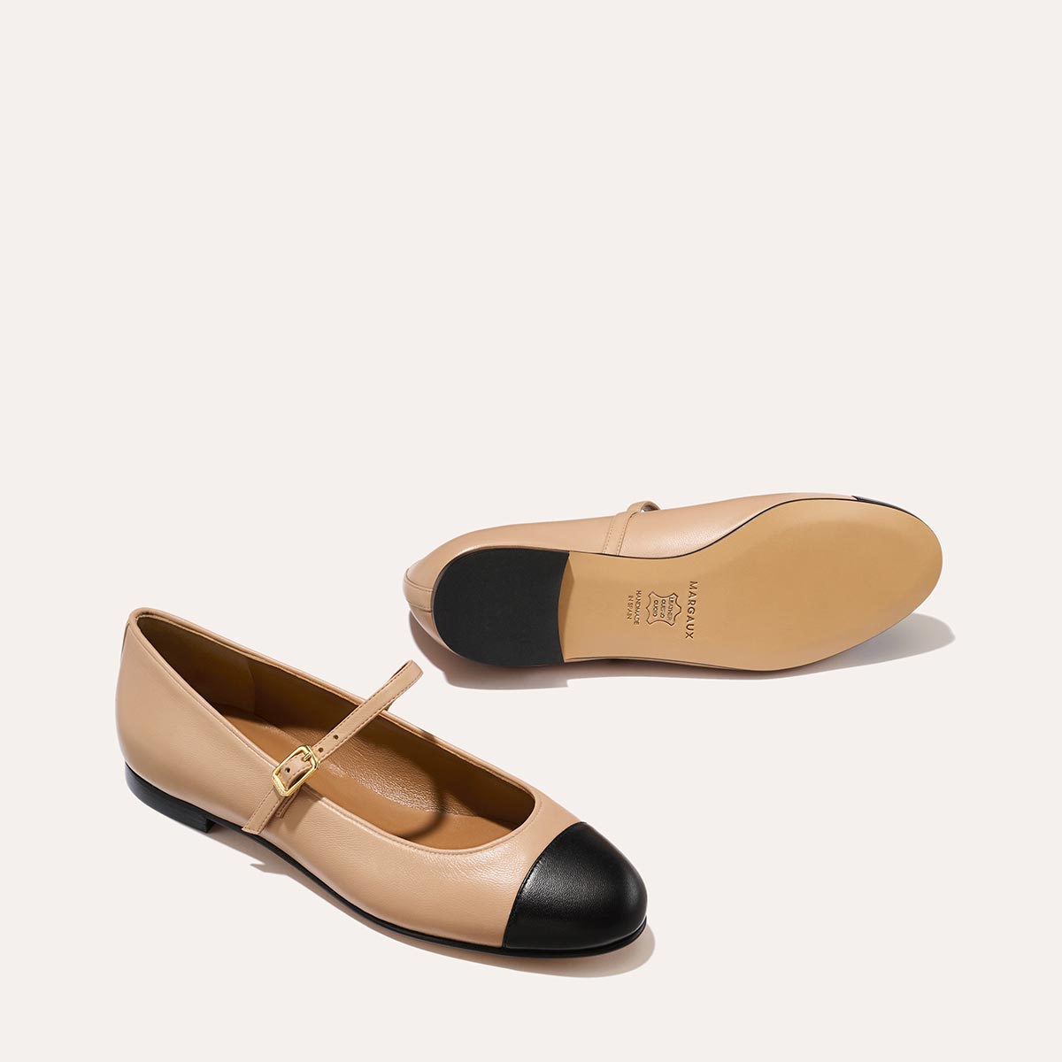 The Demi Jane in smooth Dune nappa leather, a ballet flat with a rounded toe, black cap-toe detail  and an adjustable strap for a secure fit.