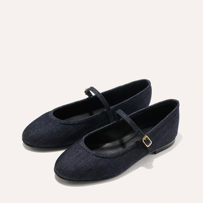 The Demi Jane - Indigo Denim by margaux-development are dark blue flats with rounded toes, low heels, and thin gold-buckled straps, shown on a light background and radiating an elegant, feminine style.