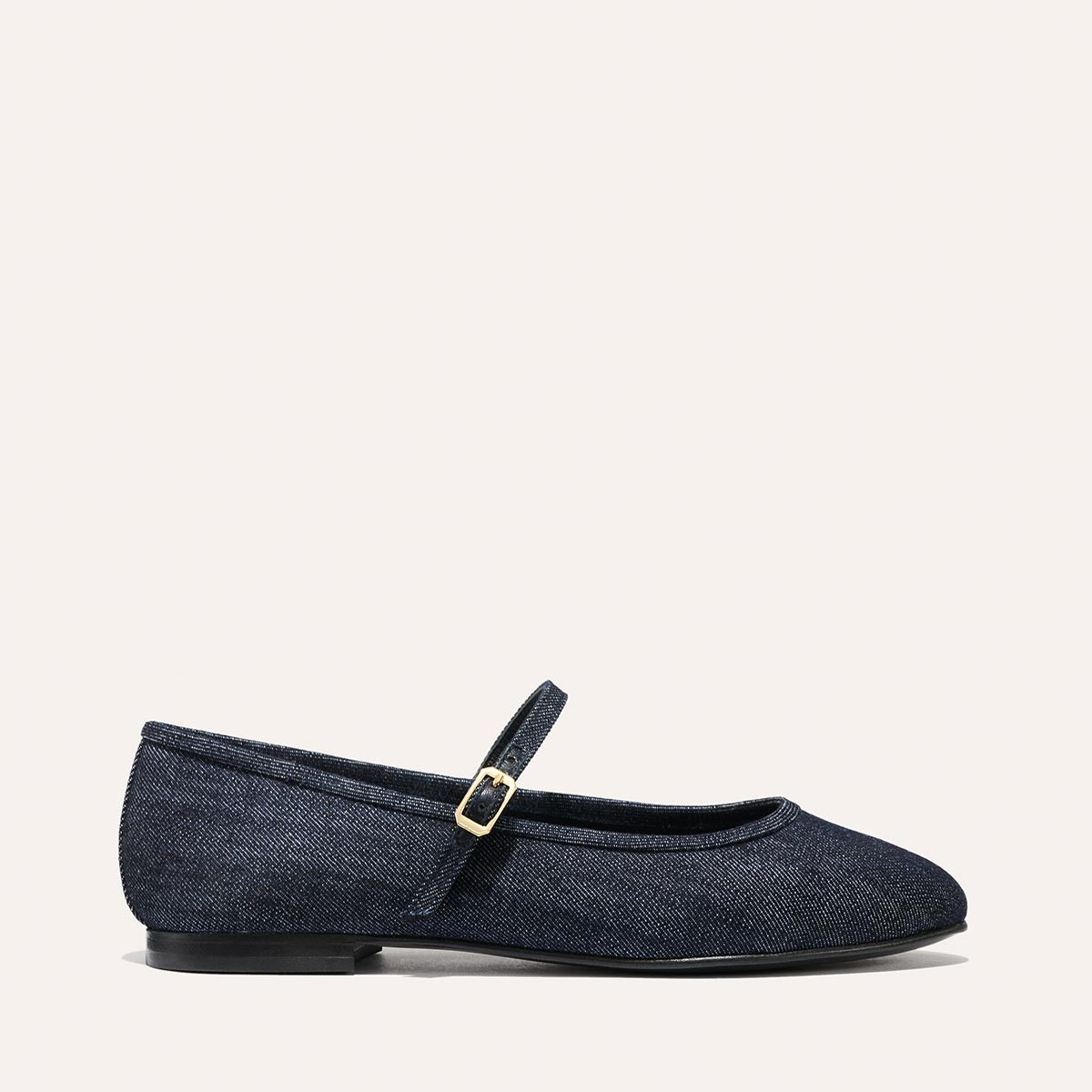 The Demi Jane - Indigo Denim by margaux-development features a dark denim Mary Jane flat with a rounded toe, slim gold-buckled strap, and black sole—an effortlessly elegant feminine touch.