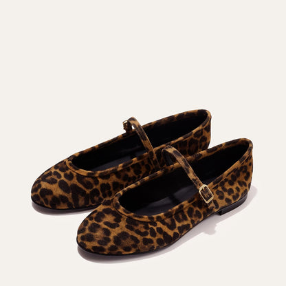 The Demi Jane - Leopard Suede by margaux-development features brown and black leopard print Mary Jane flats with rounded toes, thin straps, and gold buckles, exuding elegant femininity on a light background.