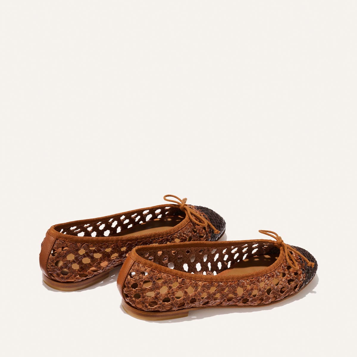 Pair of brown perforated ballet flats on a white background
