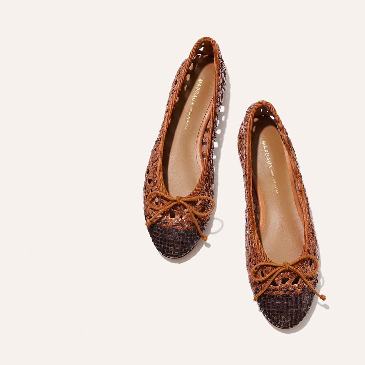 Pair of brown and black patterned flats on a white background