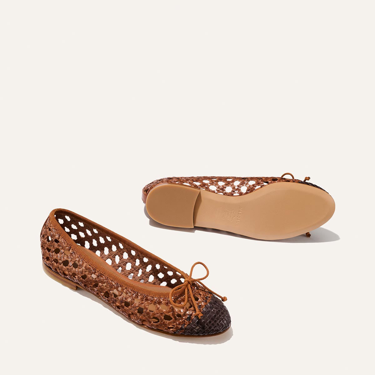 Brown perforated ballet flats with a bow on a white background