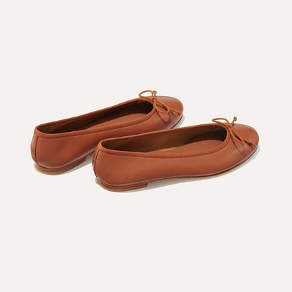 The Demi in Saddle Nappa, a comfortable ballet flat with a rounded toe and adjustable cord bow detail.