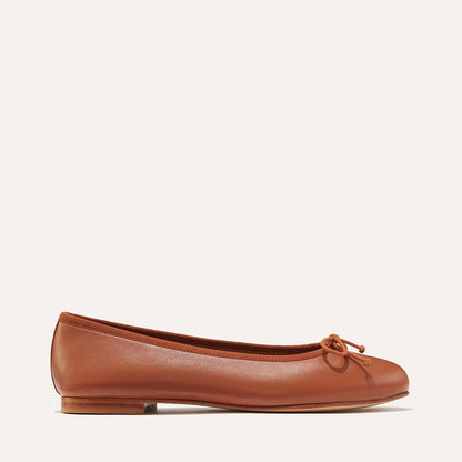 The Demi in Saddle Nappa, a comfortable ballet flat with a rounded toe and adjustable cord bow detail.
