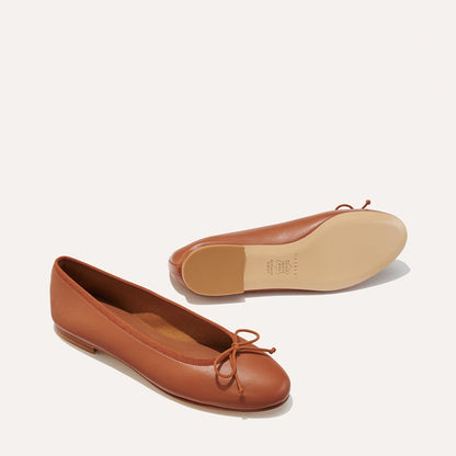 The Demi in Saddle Nappa, a comfortable ballet flat with a rounded toe and adjustable cord bow detail.
