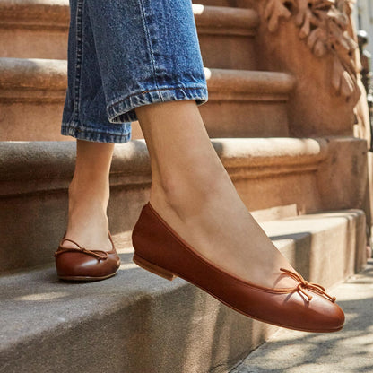 The Demi in Saddle Nappa, a comfortable ballet flat with a rounded toe and adjustable cord bow detail.
