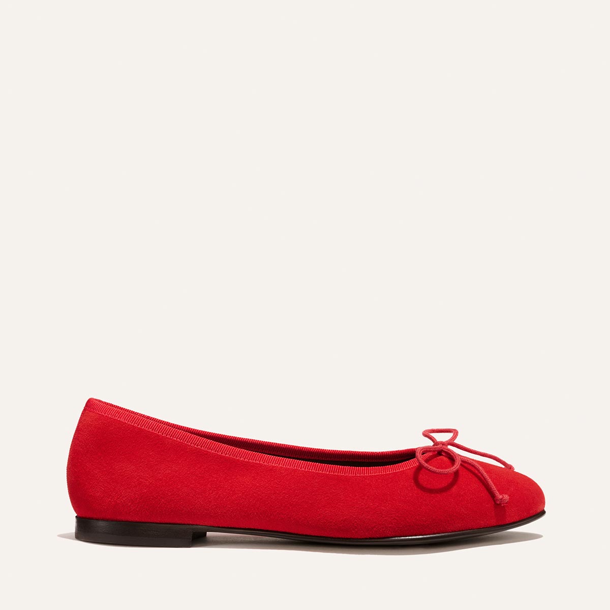 The Demi - Tomato Suede by Margaux: a handmade red ballet flat with a small bow on the toe, shown in profile against a plain light background.
