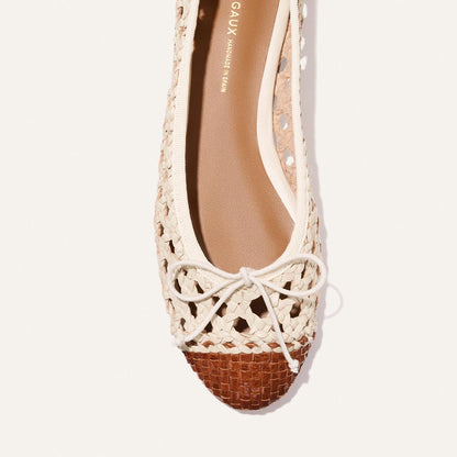 A top view of Margaux’s The Demi - Ecru and Saddle Woven Leather: a cream woven ballet flat with a brown toe cap and small front bow, set on a white background.