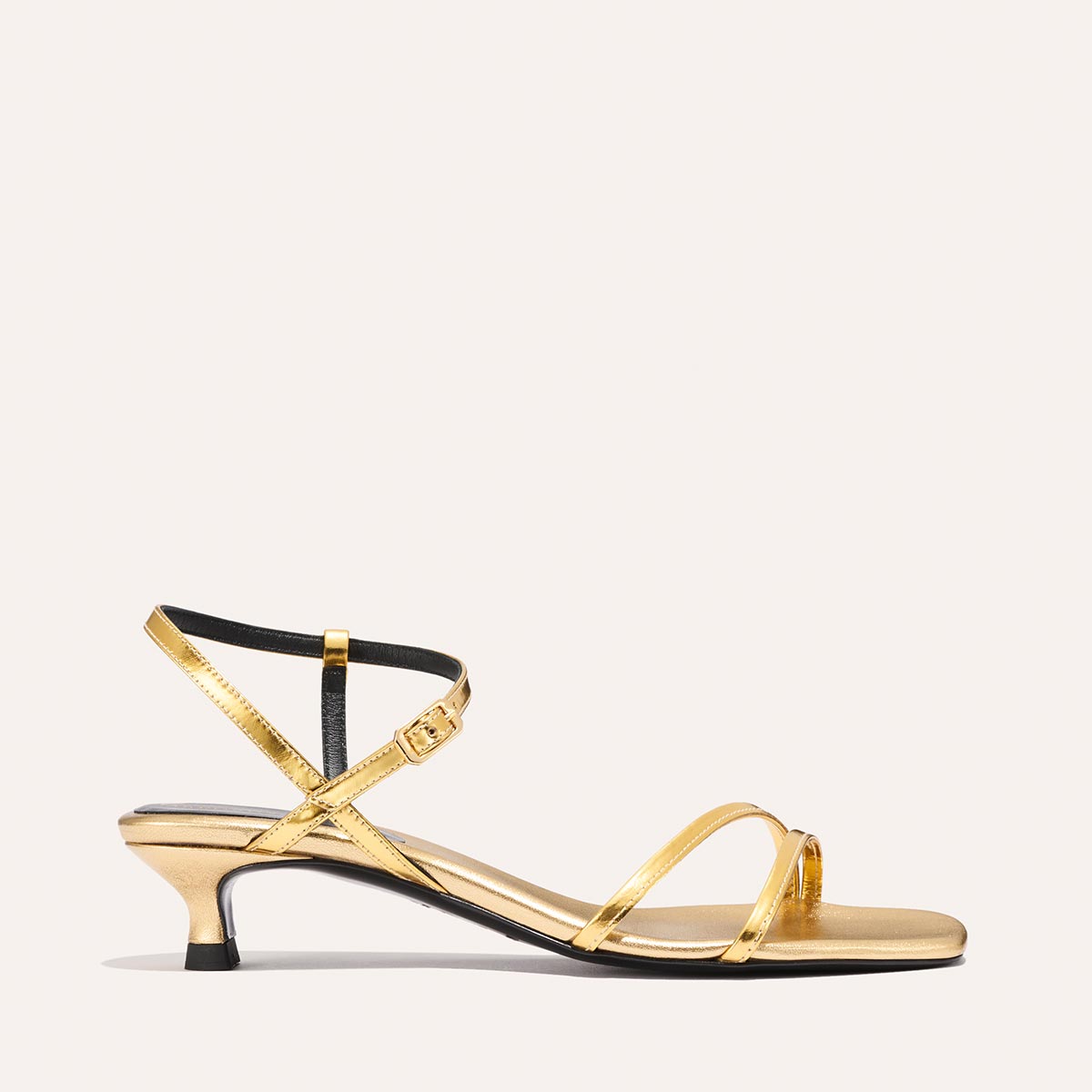 The Dylan Sandal - Gold Mirror by margaux-development features gold straps, a low kitten heel, ankle strap with small buckle, shown against a plain light background.