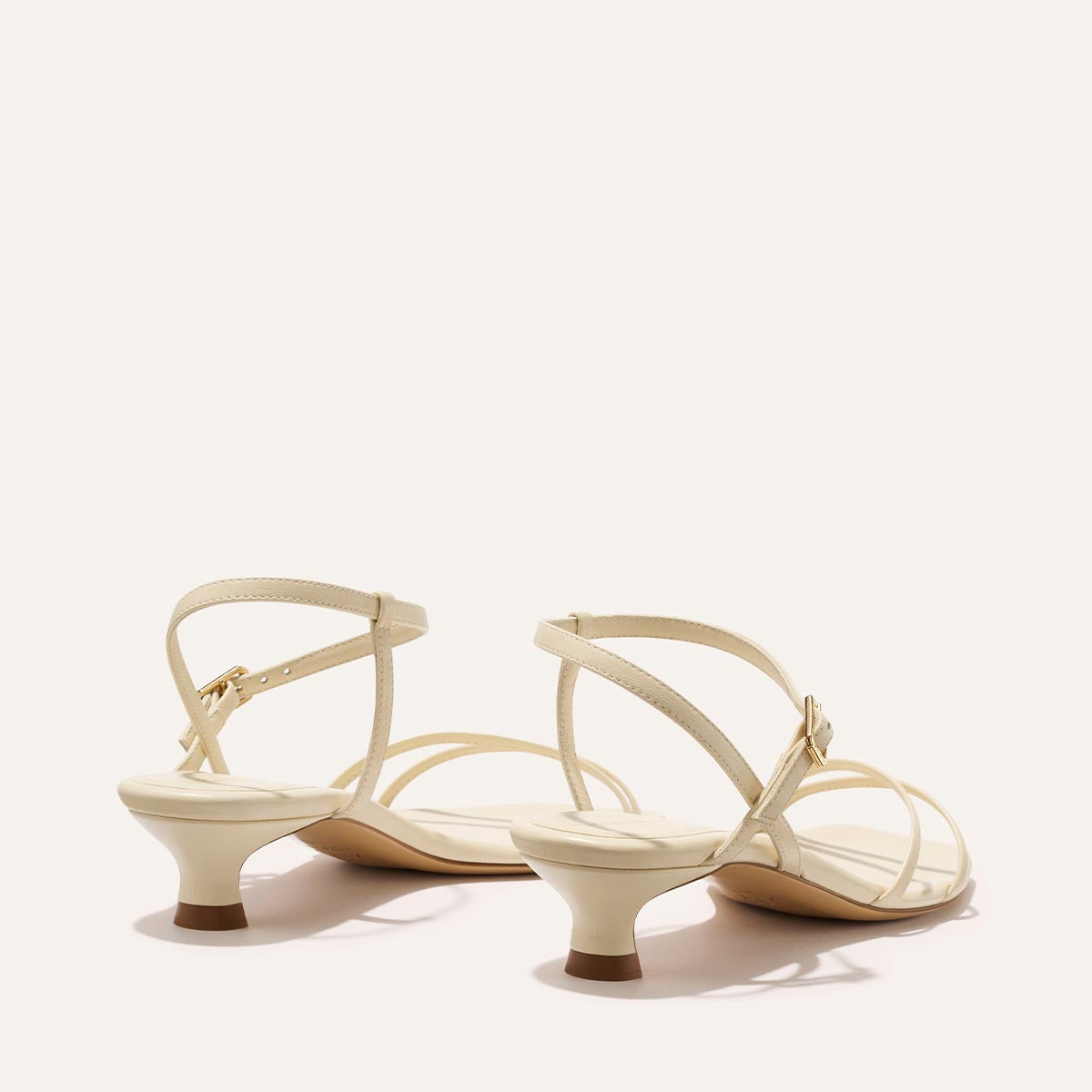 Pair of cream-colored high-heeled sandals on a light background