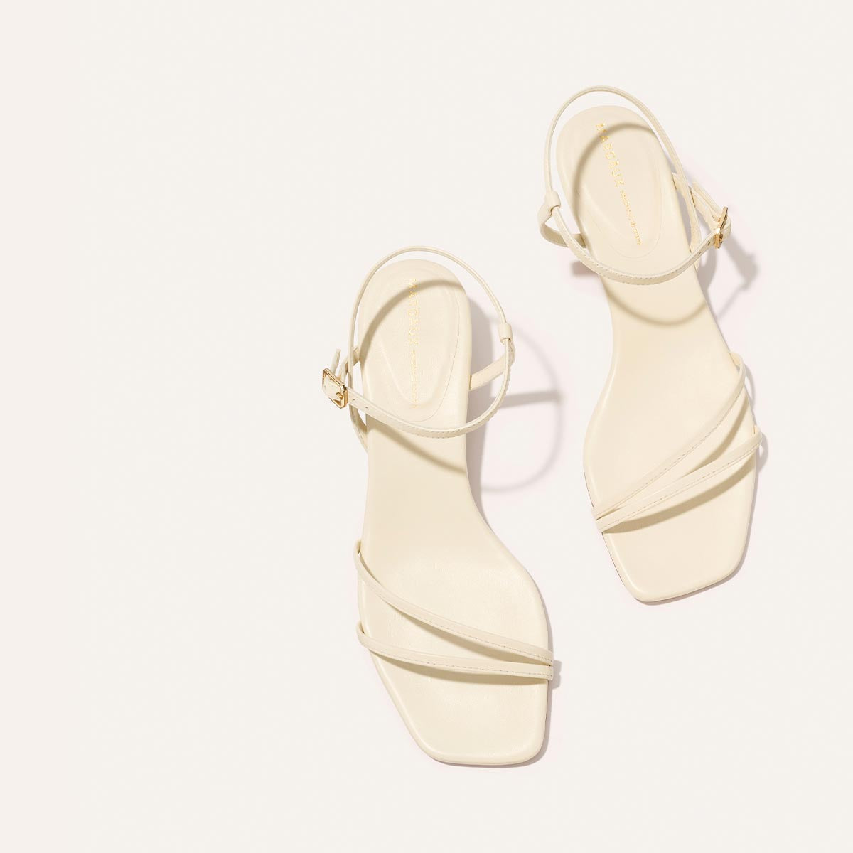 Pair of cream-colored sandals on a white background