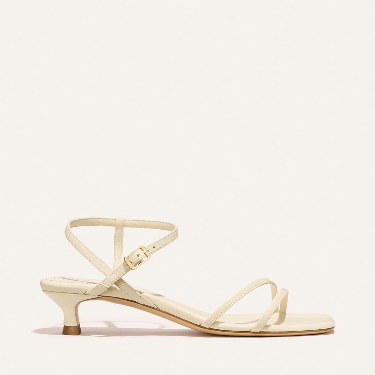 Cream colored sandal with thin straps on a white background