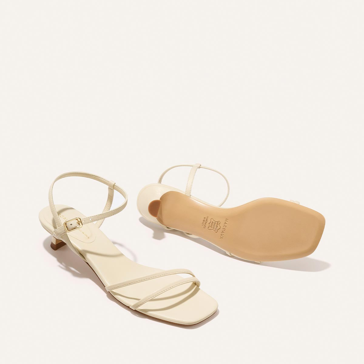 Cream colored high-heeled sandals on a white background