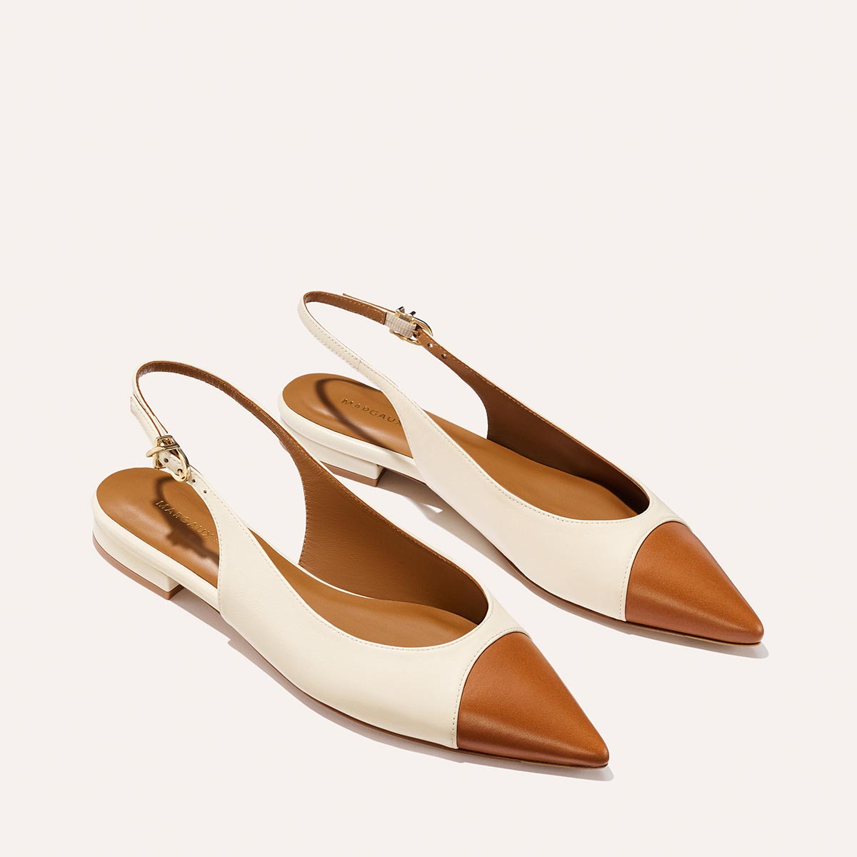 The Elise by margaux-development: women's slingback flats with pointed toes, tan brown toe cap and heel, cream sides and ankle straps—crafted in Cotton and Saddle Nappa, shown on a light background.