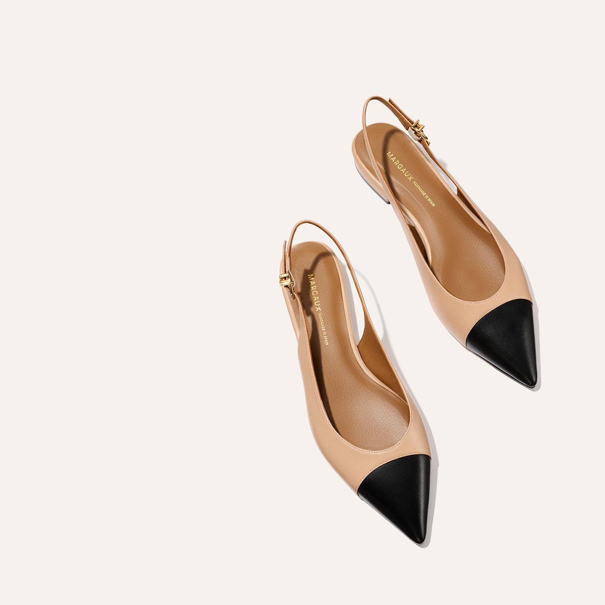 The Elise - Dune and Black Nappa by margaux-development: tan pointed-toe slingback flats with black toe caps, gold buckle accents, a sleek flat profile, and leather sole, shown on a plain light background.
