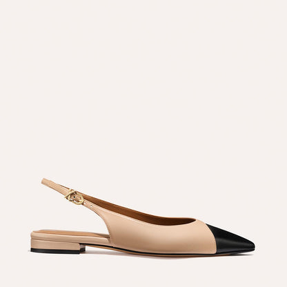 The Elise - Dune and Black Nappa by margaux-development is a beige pointed-toe slingback flat with a black cap, low heel, gold buckle strap, and leather sole, shown on a simple light background.