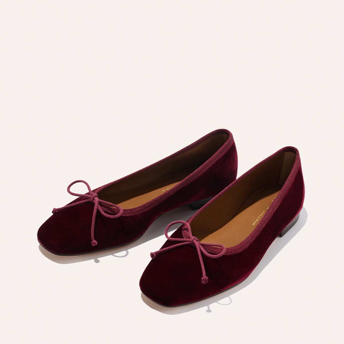 The Fonteyn - Burgundy Velvet by Margaux: handcrafted ballet flats in rich velvet with rounded toes, flat heels, and decorative front bows. Designed for comfort-first fit, shown against a light background.