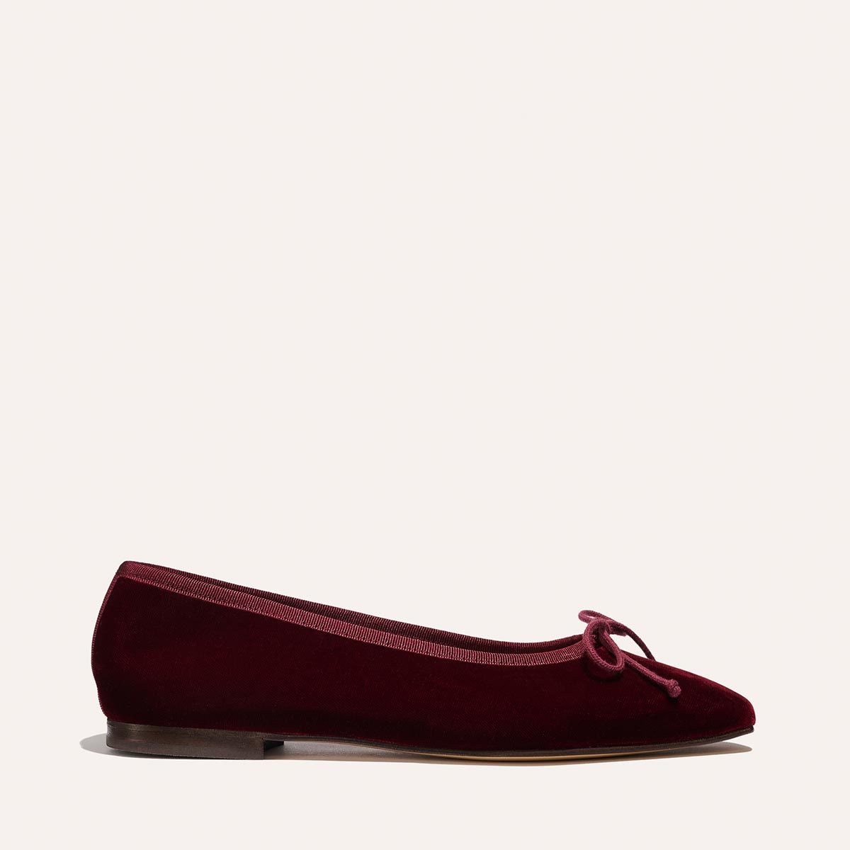 The Fonteyn by Margaux is a handcrafted burgundy velvet ballet flat with a small bow on the rounded toe, low heel, and matching trim, shown on a plain light background.