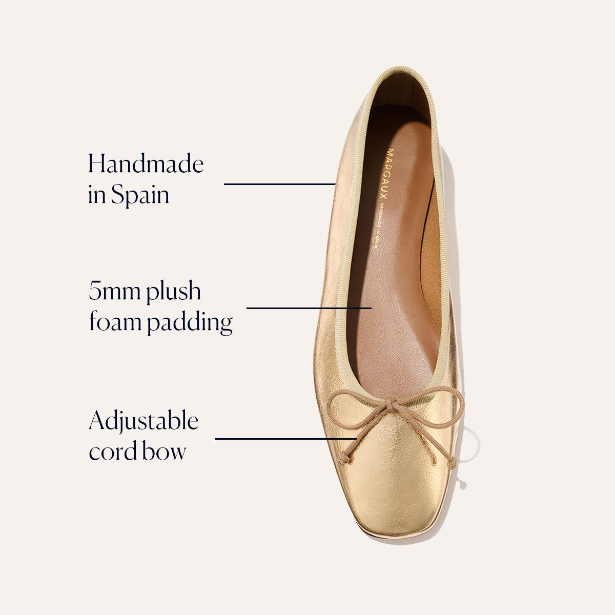 The Fonteyn - Gold Crinkle Nappa by Margaux is a gold ballet flat with a squared-off toe, handmade in Spain. It features 5mm plush foam padding, an adjustable cord bow, and a soft tan interior for signature comfort.