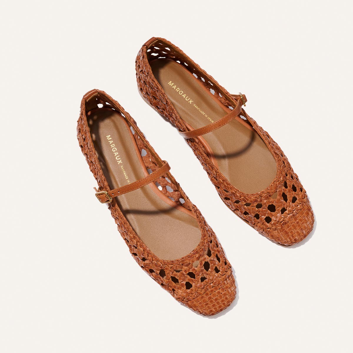 The Margaux Fonteyn Jane - Saddle Woven Leather: brown handwoven Mary Jane ballerina flats with a rounded toe and adjustable strap, shown on a white background.