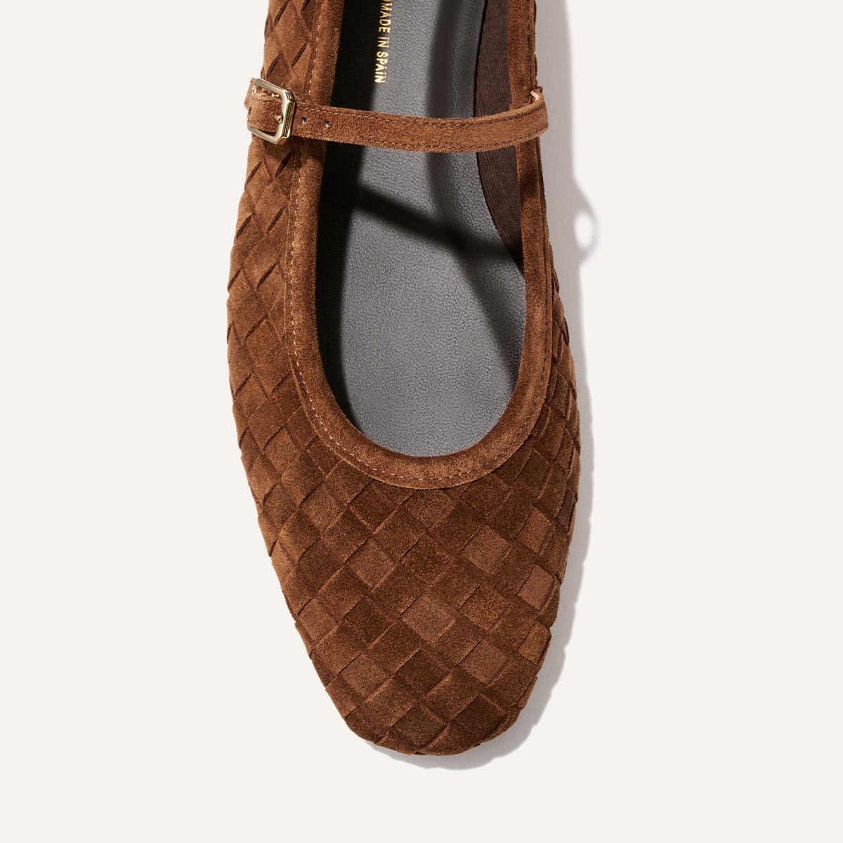 Top-down view of Margaux’s The Fonteyn Jane in Saddle Woven Pasado Suede on a white background. This Mary Jane features a slim buckle strap, rounded toe, and dark grey interior insole with "MADE IN SPAIN" visible.