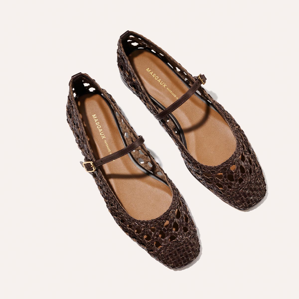 The Fonteyn Jane - Espresso Woven Leather by Margaux: brown handwoven leather flats with a closed toe, adjustable strap and gold buckle, shown on a light background. Tan insole branded with "Margaux.