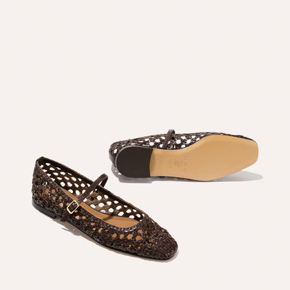 The Fonteyn Jane by Margaux: espresso handwoven leather flats with an adjustable buckle strap, open lattice design, and tan soles—one shoe upright, one on its side displaying the sole; elegant and comfortable ballerina style.