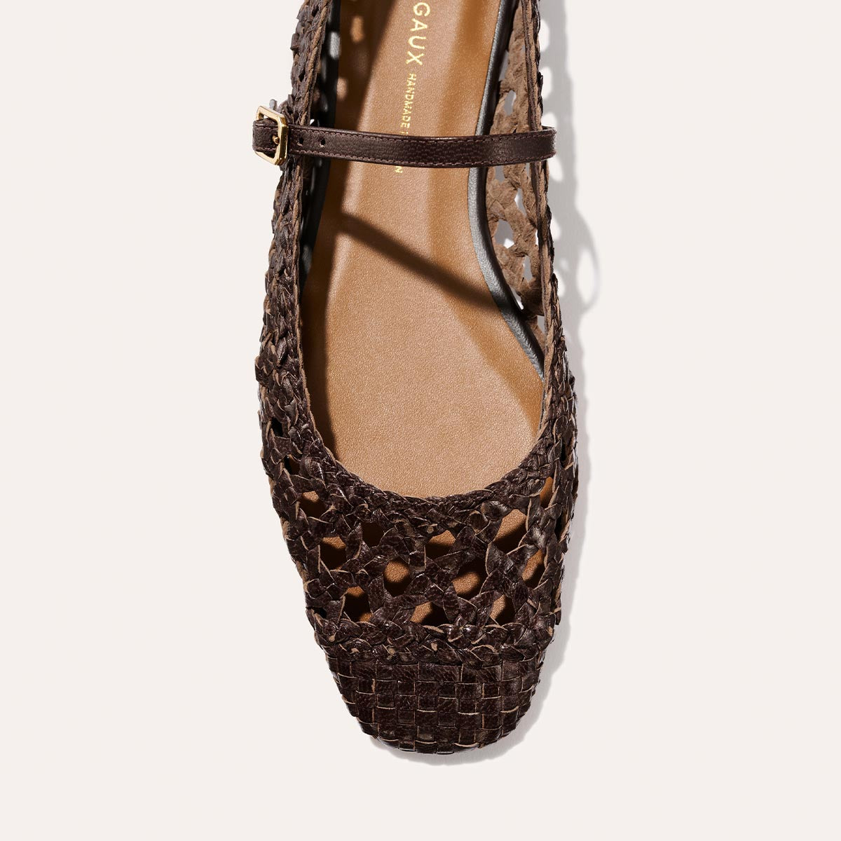 Top view of The Fonteyn Jane - Espresso Woven Leather flat by Margaux features a brown handwoven leather, closed rounded toe, and an adjustable strap with gold buckle, displayed on a light background.