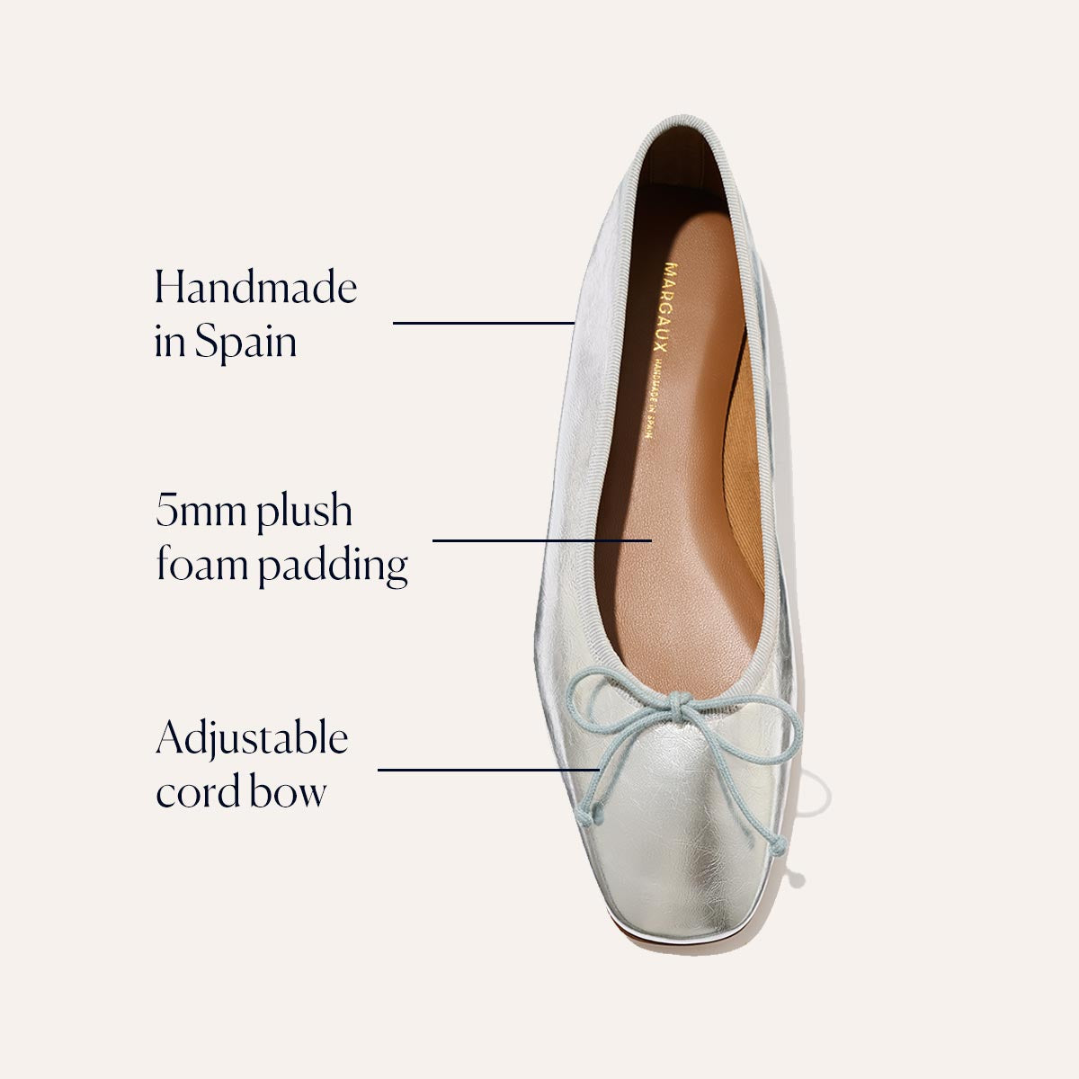 Top view of Margaux's The Fonteyn - Silver Crinkle Nappa ballet flat with text highlighting: “Handmade in Spain,” “5mm plush foam padding,” and “Adjustable cord bow” at the toe.