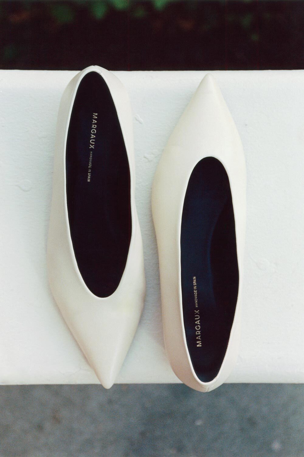 Pair of white high-heeled shoes with black soles on a white surface.