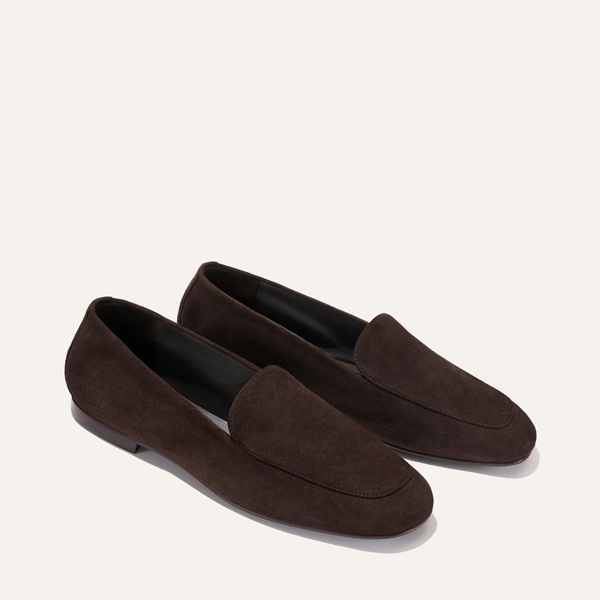 The James Loafer - Molasses Suede by Margaux features a simple, classic design in dark brown suede with a tailored fit and is expertly crafted using sacchetto construction, shown on a plain light background.