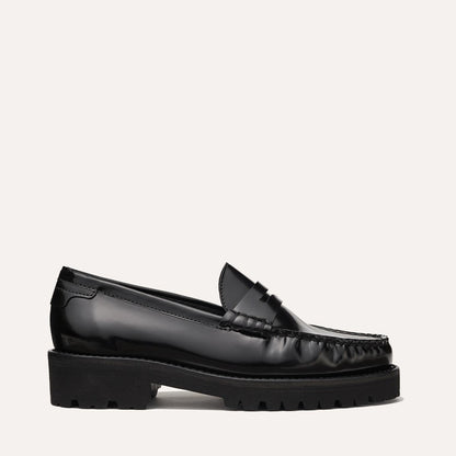 The Margaux Louisa Loafer First Edition in Black Calf, featuring a shiny leather-lined design and chunky textured rubber sole, is displayed in side profile against a plain light background.