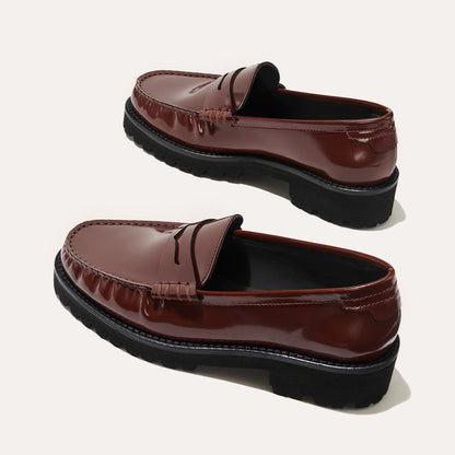 A pair of Margaux The Louisa Loafer First Edition - Hickory Calf, with black rubber soles and leather lining for comfort, displayed on a light background. Each shoe is angled differently to highlight the detailed design.