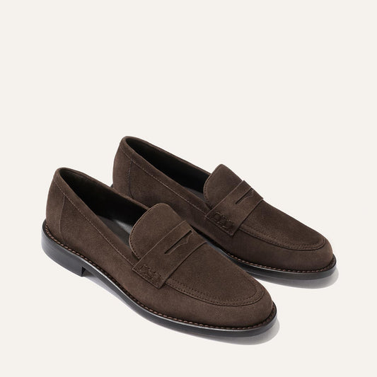 A pair of Margaux’s The Marlowe Loafer in Umber Suede, featuring black soles, displayed on a plain light background.