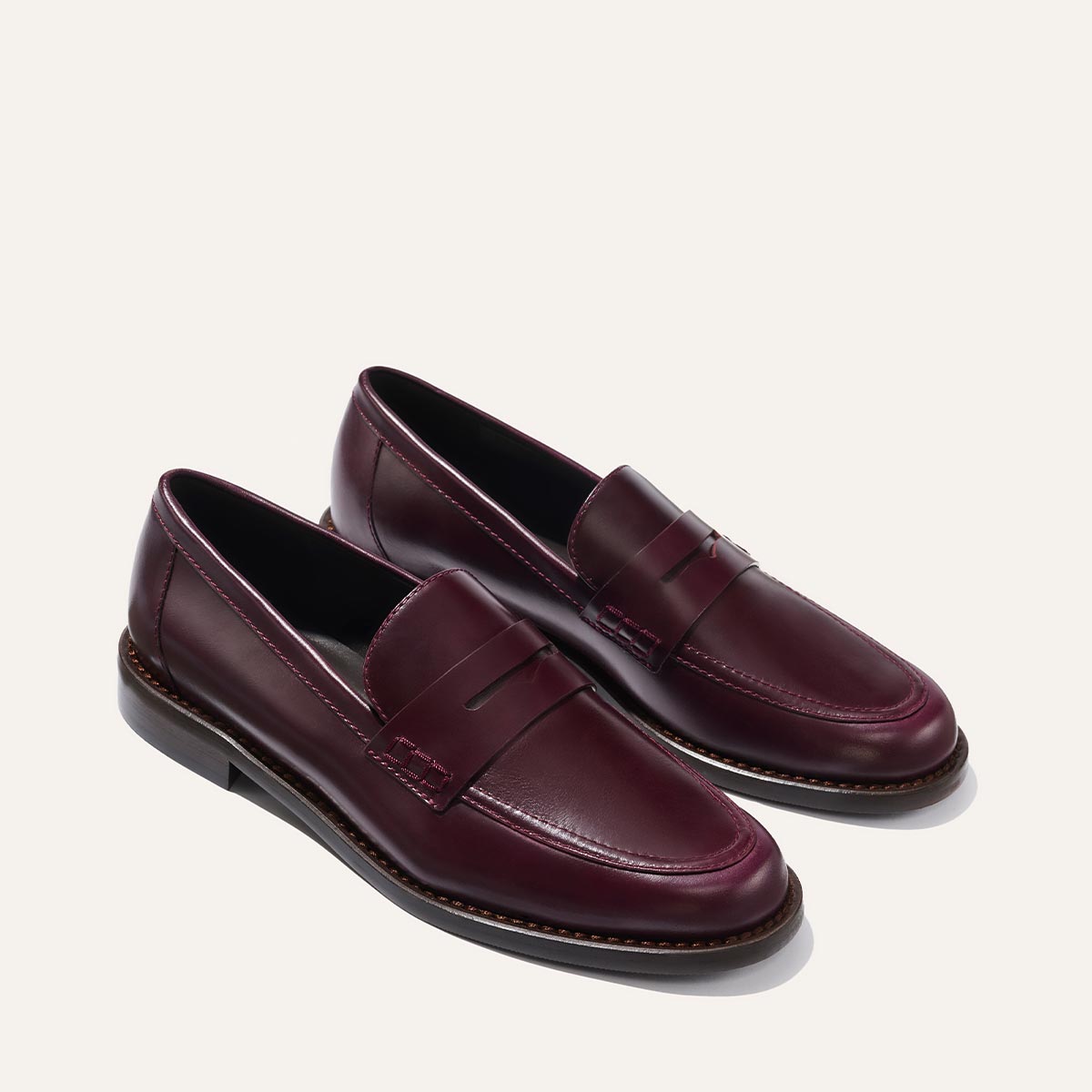 The Marlowe Loafer - Burgundy Calf by margaux-development features rounded toes, low stacked heels, and visible stitching along the soles, presented on a light background.